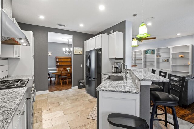 kitchen with white cabinets, hanging light fixtures, light tile patterned flooring, black refrigerator, and sink