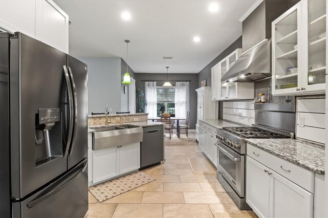 kitchen featuring white cabinets, light tile patterned flooring, stainless steel appliances, and wall chimney range hood