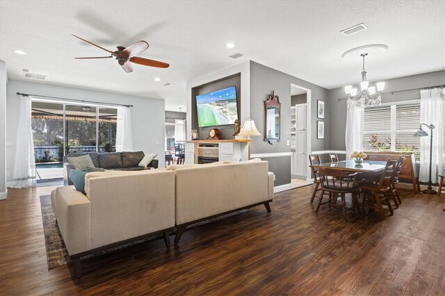 living room featuring ceiling fan with notable chandelier, a textured ceiling, wood-type flooring, and a wealth of natural light