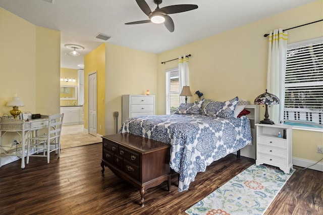 bedroom featuring ensuite bathroom, wood finished floors, a ceiling fan, visible vents, and baseboards