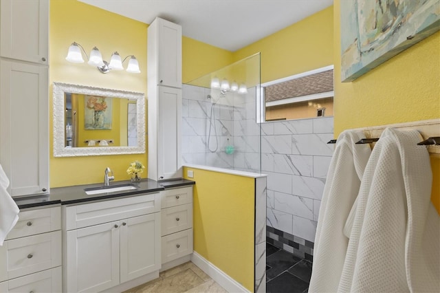 bathroom featuring tile patterned floors, a tile shower, and vanity