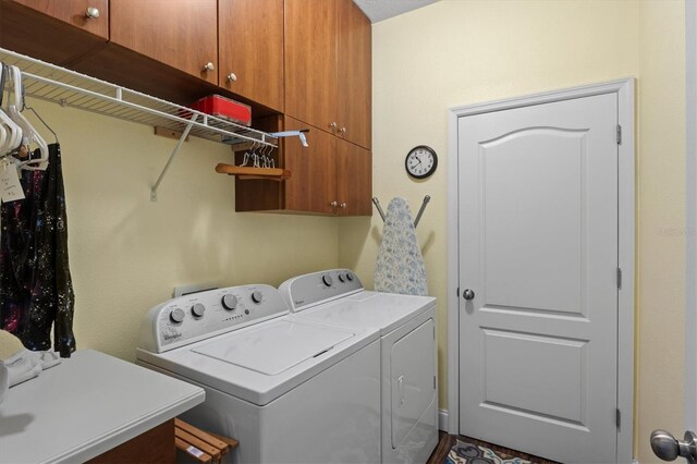 clothes washing area featuring washer and dryer and cabinets