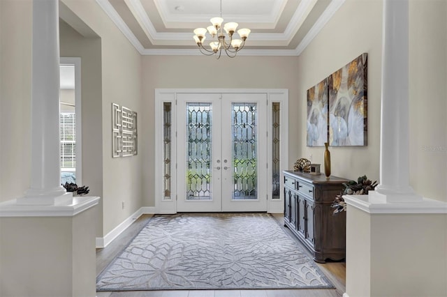 entrance foyer with decorative columns, crown molding, an inviting chandelier, and light hardwood / wood-style flooring