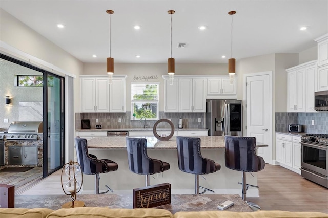 kitchen with hanging light fixtures, stainless steel appliances, and a kitchen island