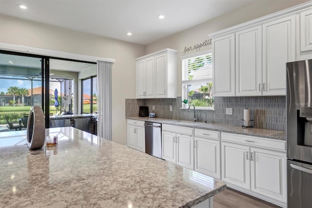 kitchen with light stone countertops, sink, tasteful backsplash, appliances with stainless steel finishes, and white cabinets