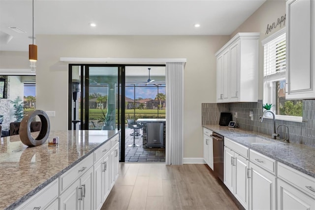 kitchen with white cabinetry, sink, dishwasher, and light stone counters