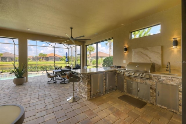 view of patio with a lanai, sink, a grill, and exterior kitchen