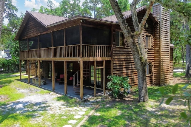 rear view of house featuring a sunroom, a patio area, and a yard