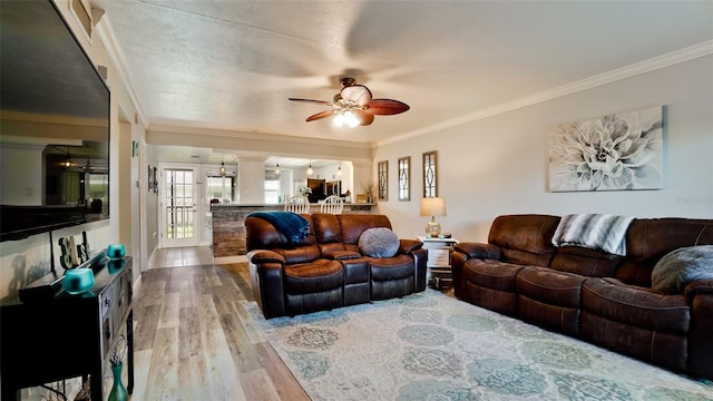 living room featuring ceiling fan, wood-type flooring, a textured ceiling, and crown molding