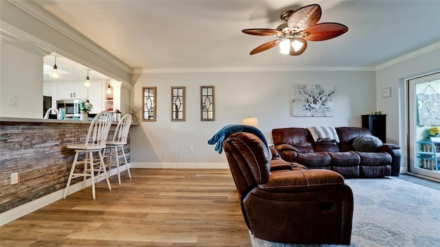 living room with ceiling fan, plenty of natural light, light hardwood / wood-style floors, and crown molding