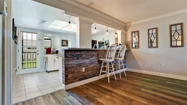 bar featuring light hardwood / wood-style flooring, white cabinets, sink, and a skylight