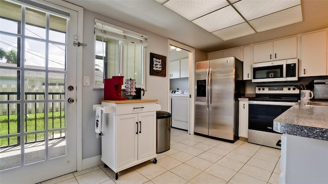 kitchen featuring appliances with stainless steel finishes, light tile patterned floors, white cabinets, and a healthy amount of sunlight