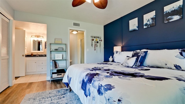 bedroom with connected bathroom, light wood-type flooring, ceiling fan, and a closet