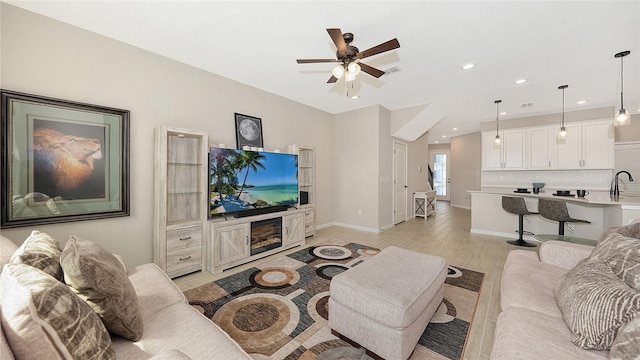 living room with light hardwood / wood-style floors, ceiling fan, and sink