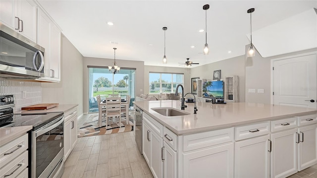 kitchen featuring white cabinets, ceiling fan with notable chandelier, sink, and stainless steel appliances