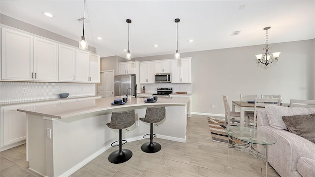 kitchen with a center island with sink, white cabinets, and stainless steel appliances