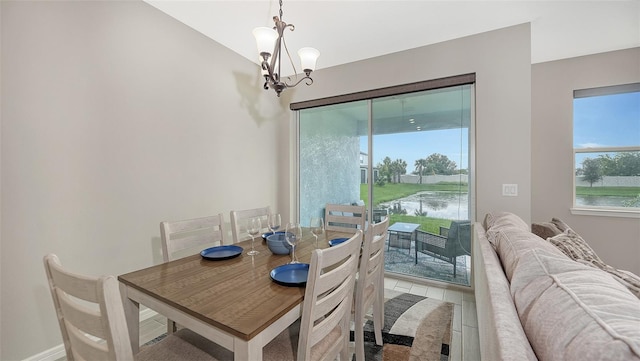 dining room with light hardwood / wood-style flooring, a water view, and a chandelier