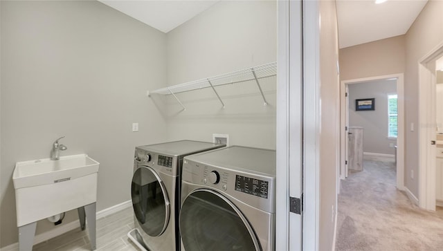 laundry area with separate washer and dryer, light carpet, and sink