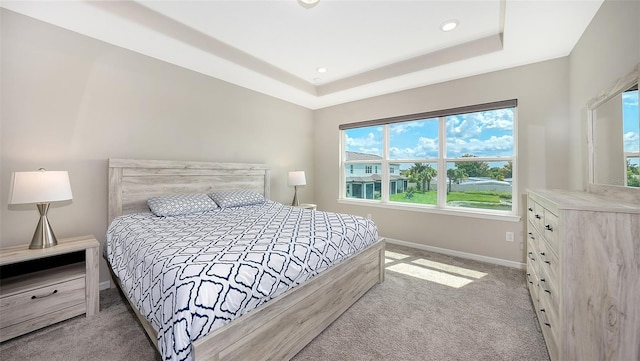 bedroom with a tray ceiling and light colored carpet