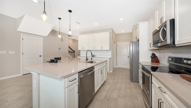 kitchen featuring a center island with sink, decorative light fixtures, white cabinetry, and appliances with stainless steel finishes