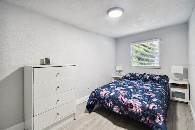 bedroom with a textured ceiling and light hardwood / wood-style floors