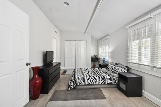 bedroom with vaulted ceiling with beams, light hardwood / wood-style flooring, and multiple windows