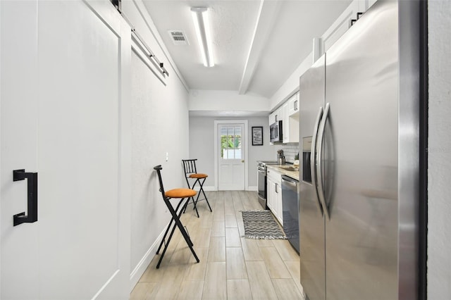 kitchen with light hardwood / wood-style flooring, white cabinets, and stainless steel appliances