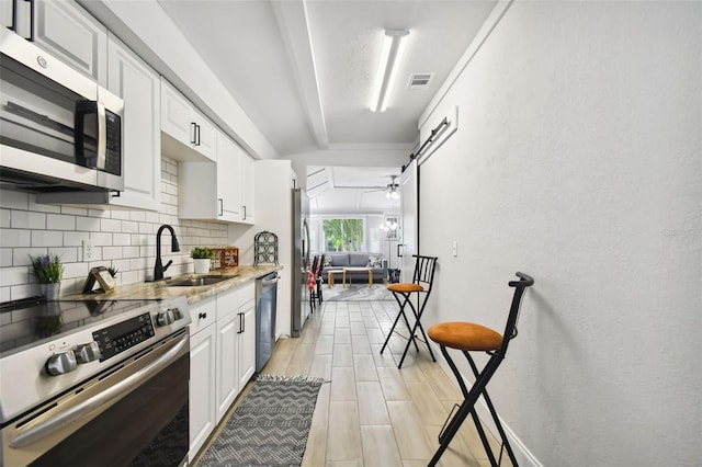 kitchen with appliances with stainless steel finishes, sink, ceiling fan, and white cabinetry