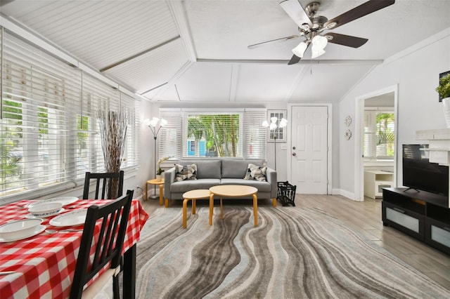 living room featuring light hardwood / wood-style floors, ceiling fan with notable chandelier, vaulted ceiling, and a healthy amount of sunlight