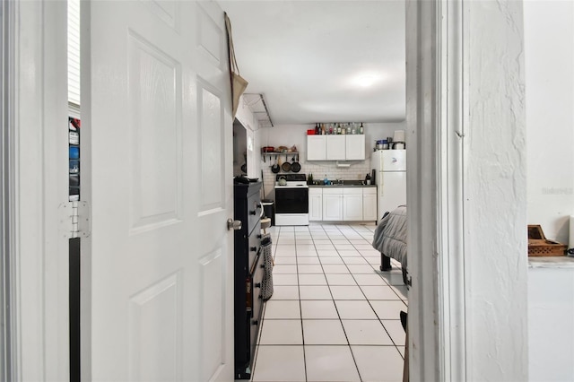 kitchen featuring tasteful backsplash, light tile patterned floors, white appliances, and white cabinetry