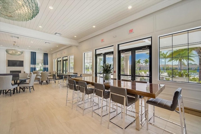 dining space featuring beam ceiling, wooden ceiling, a fireplace, and french doors