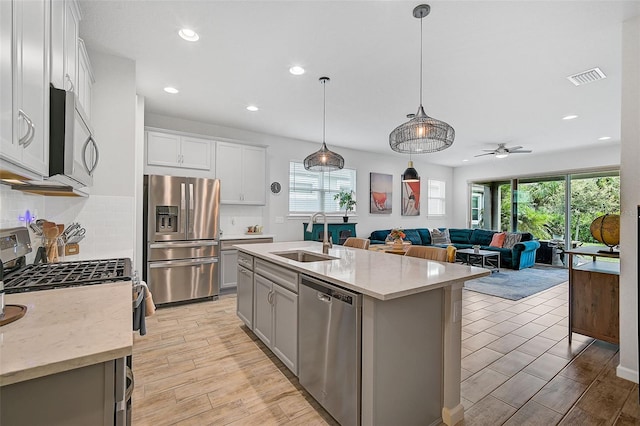 kitchen with a healthy amount of sunlight, sink, an island with sink, and stainless steel appliances