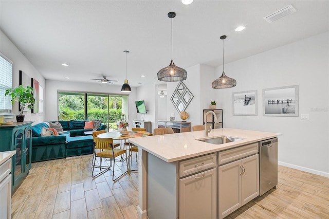 kitchen with dishwasher, sink, pendant lighting, light hardwood / wood-style floors, and a kitchen island with sink