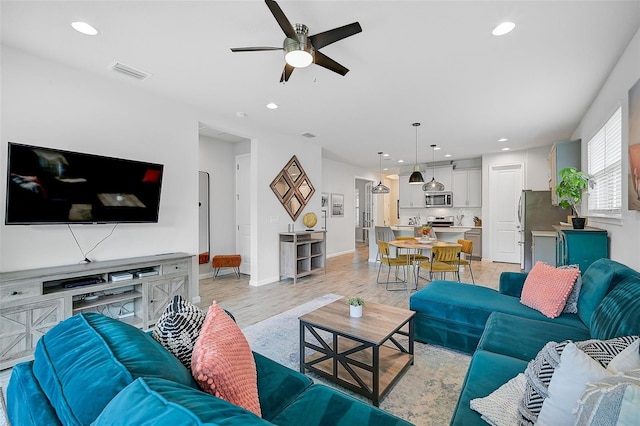 living room featuring ceiling fan and light hardwood / wood-style flooring