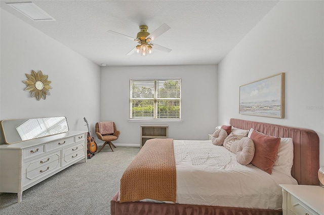 bedroom featuring a textured ceiling, light colored carpet, and ceiling fan