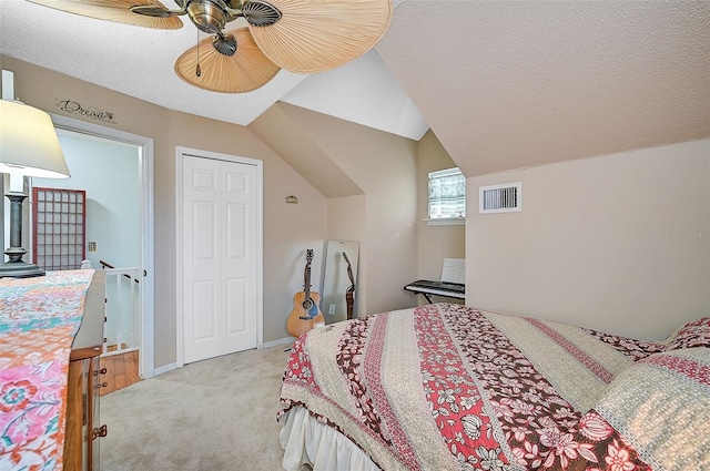 carpeted bedroom with ceiling fan, a closet, a textured ceiling, and vaulted ceiling