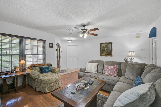 living room featuring ceiling fan, wood-type flooring, and a textured ceiling