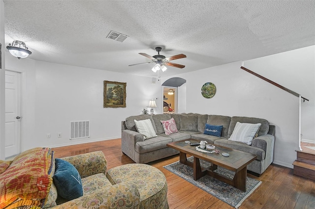 living room with dark hardwood / wood-style floors, ceiling fan, and a textured ceiling