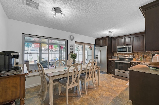 dining space with sink, a healthy amount of sunlight, and a textured ceiling