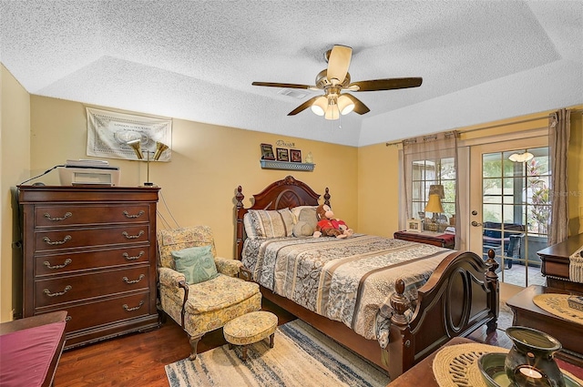 bedroom with ceiling fan, dark hardwood / wood-style floors, a raised ceiling, and access to outside