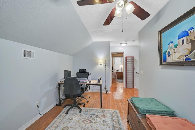 office space featuring ceiling fan, light hardwood / wood-style floors, lofted ceiling, and a textured ceiling