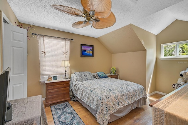 bedroom with ceiling fan, light hardwood / wood-style flooring, and vaulted ceiling