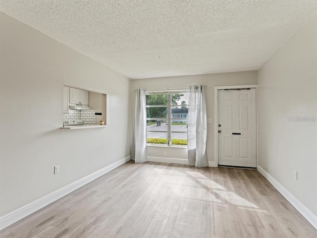 unfurnished room with light hardwood / wood-style flooring and a textured ceiling