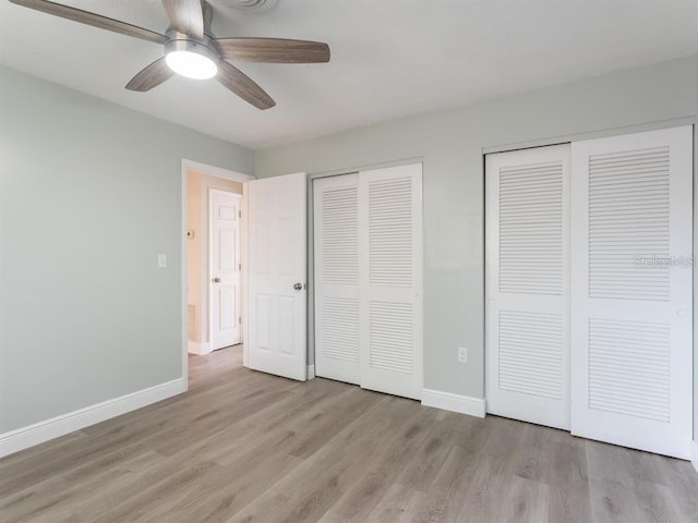 unfurnished bedroom with ceiling fan, two closets, and wood-type flooring