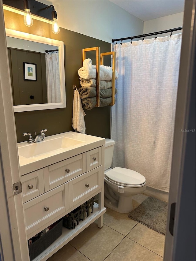 bathroom with toilet, vanity, and tile patterned flooring