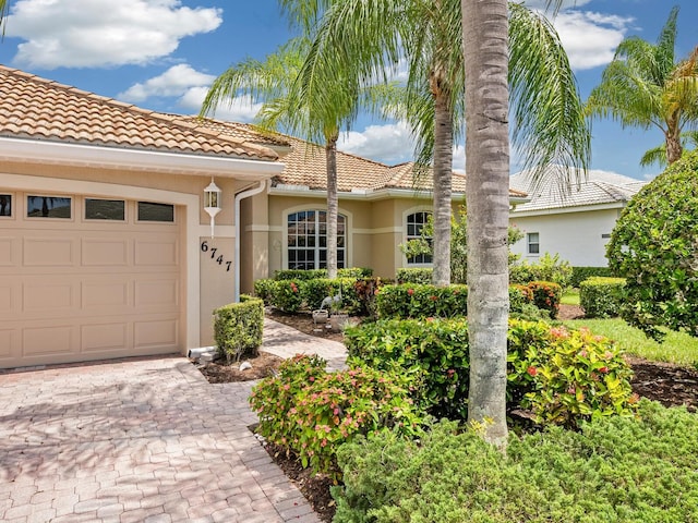 mediterranean / spanish home with a tile roof, an attached garage, and stucco siding