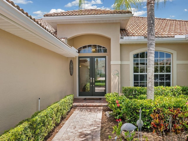 entrance to property with stucco siding, a tiled roof, and french doors