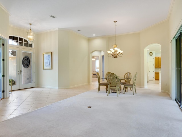 carpeted dining room with a healthy amount of sunlight, arched walkways, a notable chandelier, and tile patterned floors