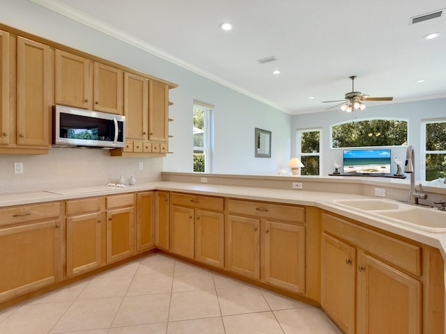 kitchen with visible vents, white stovetop, stainless steel microwave, crown molding, and a sink