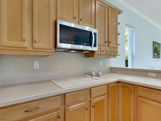 kitchen with light countertops, white electric stovetop, stainless steel microwave, and light brown cabinets